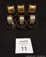 Set of six gold tone and six silver tone napkin rings on black background