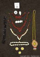 Collection of natural shell and beaded jewellery including necklaces, bracelets, and earrings displayed on a black background.