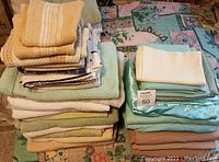 Overall view of multiple stacks of towels and bedding on a floral patterned surface