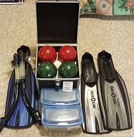 Full view of flippers, bocce balls in case, two blue containers, and snorkelling mask snorkel attachments.
