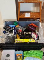 Bin containing car wash supplies, black hair dryer, power plugs, mid-sized hand tools, and assorted items