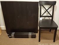 Photo of black wooden dining table top detached legs placed alongside