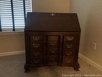 Front view of closed mahogany secretary desk showing drop-front and metal hardware.