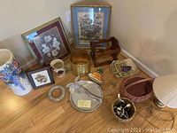 Photo showing entire lot including floral pictures, ceramic umbrella holder, baskets, lamp, serving platters, and wine holder on floor.