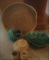 Woven tray, small baskets, and Blue Mountain Pottery dishes arranged on floor
