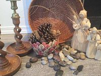 Woven basket, pottery bowl with pine cones, natural rocks, corn husk dolls, and hand carved wooden squirrel displayed together.