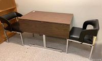 Table between two black vinyl chairs with chrome frames