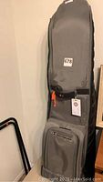 Gray Champion travel golf bag with front zippered pouch and orange zipper pull displayed upright.