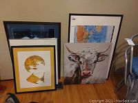 Three framed prints grouped together: signed fish print, bull painting, and large world map
