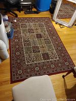 Full view of the rectangular Ikea Valby Ruta area rug laid on a hardwood floor, showing the central and border patterns.