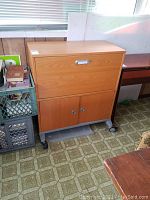 Front view of the rolling wooden storage cabinet showing two doors bottom section and pull-out file drawer upper section.
