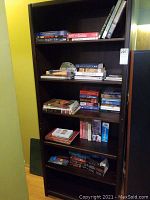 Shelf filled with assorted books of various sizes and colors showing spines and covers