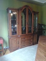 Front view of the wooden china cabinet showing glass doors, storage drawers, and lower wooden cabinets.