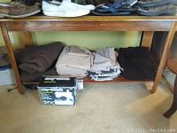 Photo showing five sets of folded linens in neutral colors placed on a wooden bench with the Easy-Stitch sewing machine box in front.