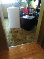 Photo showing both refrigerators side by side, white Diplomat and black Danby, placed on floor near a doorway.