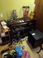 The three-level wooden shelf with decorative glass and ceramic items on top and inside, visible scratches and wear on surface.