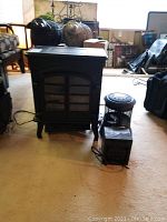 Full view of electric fireplace with two space heaters placed in front of it.