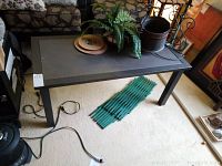 Full view of rectangular metal coffee table showing tabletop and legs, surrounded by other household items.