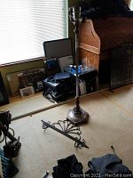 Floor lamp 58in tall with metal base and pole, untested, standing upright near a wooden roll-top desk.