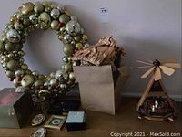 Christmas ornament wreath, four coaster frames, cardboard box, and wooden nativity pyramid on table
