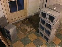 Four concrete cinder blocks positioned near a door in basement, showing shape and condition.