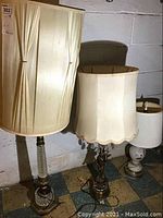 Photo showing three vintage lamps grouped against a white wall, with different styles of lampshades and bases visible.