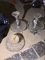 Two matching vintage glass serving dishes with pedestal bases and fluted edges, one with metal support, plus one additional glass serving dish with geometric pattern