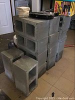 Stack of gray cinder blocks with some items placed on top such as a carrying case and small tiles.
