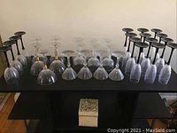 Top down view of 31 glassware pieces arranged on a black table with a decorative textured square storage box below