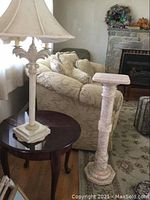 Round dark wood side table with lamp and pedestal stand in living area