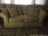 Front view of the floral-patterned love seat with four matching throw pillows on it.