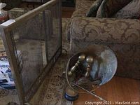 Fireplace screen positioned oblique showing mesh and brass frame.