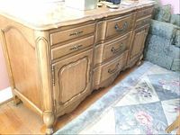 Full frontal view of the wooden buffet showing the drawers, cabinet doors, and handles against a floor and rug background.