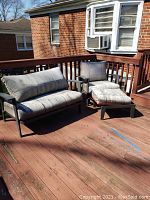 Outdoor love seat, armchair, and ottoman set on wooden deck. Cushions are gray and soiled. Furniture metal frames show wear.