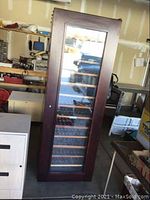 Front angled view of tall wooden wine fridge against garage backdrop