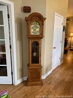 Full front view of grandfather clock showing entire oak case and base