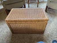 Top and front view of tan wicker trunk showing woven wicker texture and rectangular shape.