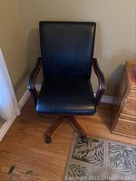 Front view of chair showing seat back, seat cushion, wooden arms, and caster base