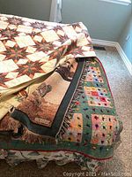 Four different quilts and blankets shown stacked and displayed on bed