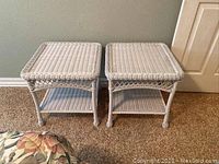 Photo showing both white resin wicker side tables side by side on carpeted floor against a pale green wall near a cream door.