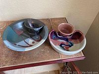 Two art pottery serving bowls with dip and chips design on a tiled table, colors include blue, black, maroon, white, reddish, and blue swirl pattern.