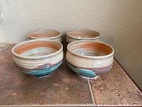 Four ceramic pottery bowls with earthy glaze, showing colors and patterns