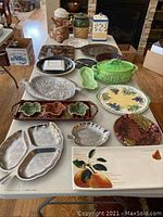 Full view of assorted serving ware on a table including platters, canisters, and one vintage elephant cookie jar.