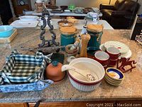 Overview of kitchenware assortment on countertop showing canisters, bowls, bread baskets, utensil, and napkin holder
