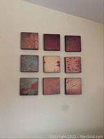 Nine 11x11 inch square Asian motif wall art pieces arranged in a 3x3 grid on a light wall.