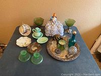 Photo showing all collectibles on table including radio figurine, green glass, teacup, tray, and assorted items