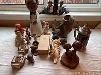 Wide view of assortment on table showing German stein, figurines, wood carvings, and boxes
