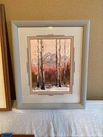 Full view of framed watercolor print showing scene of birch trees and distant mountains in gray wooden frame.