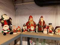 Shelf view showing plush Santa, small figurines and large painted gourd Santa at center