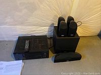 Denon AVR-1312 AV receiver with remote, four satellite speakers, center channel speaker, and subwoofer arranged on floor.